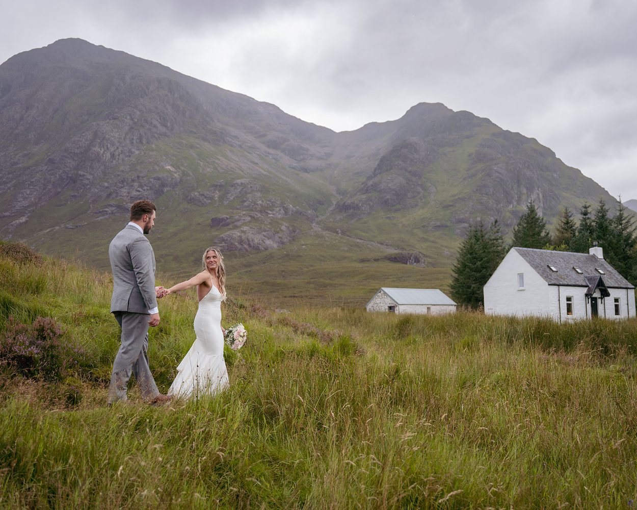A couple kissing beside a Scottish loch with mountains behind